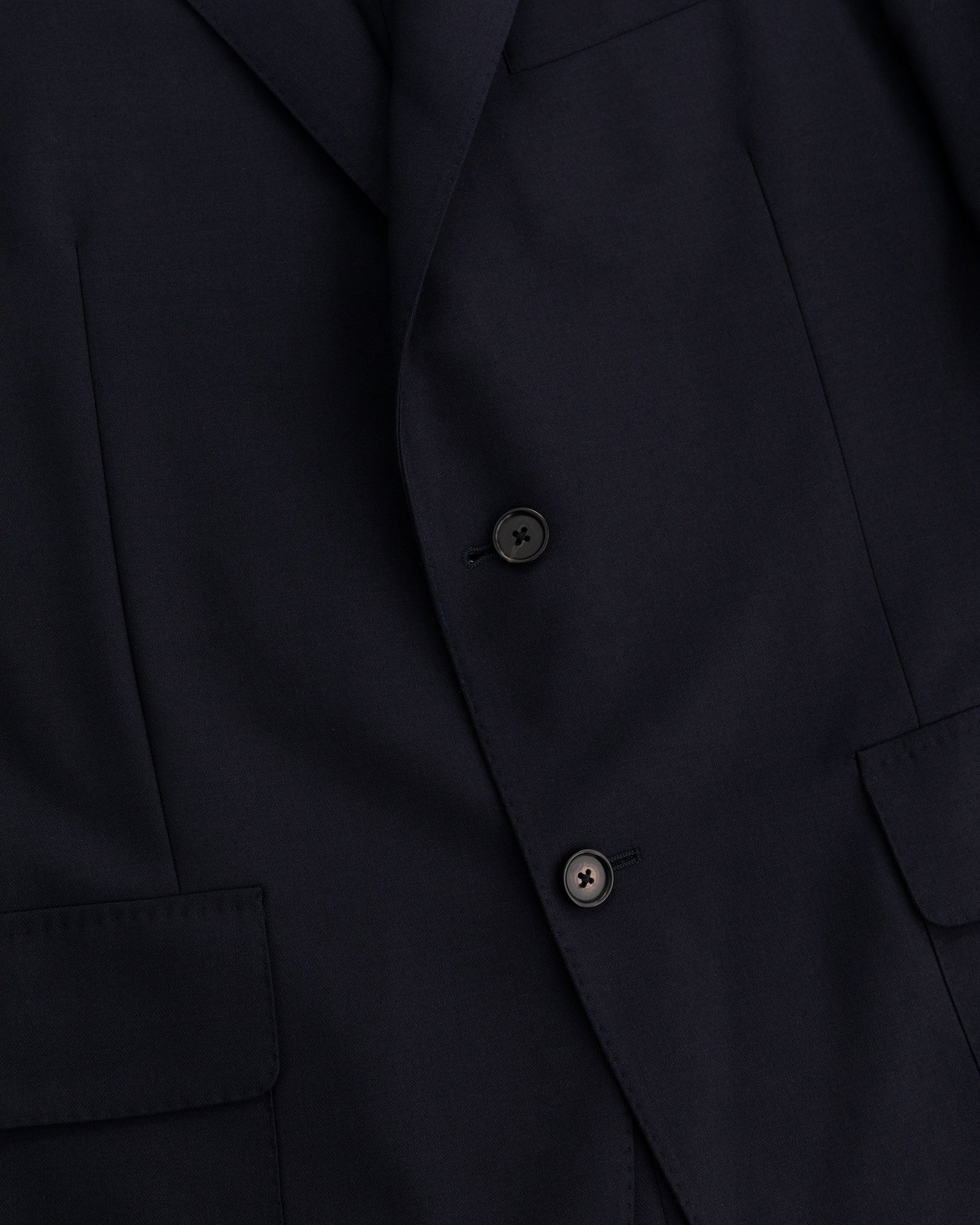 Close-up of the Tropical Wool Suit Jacket in dark navy with two black buttons and front flap pockets.
