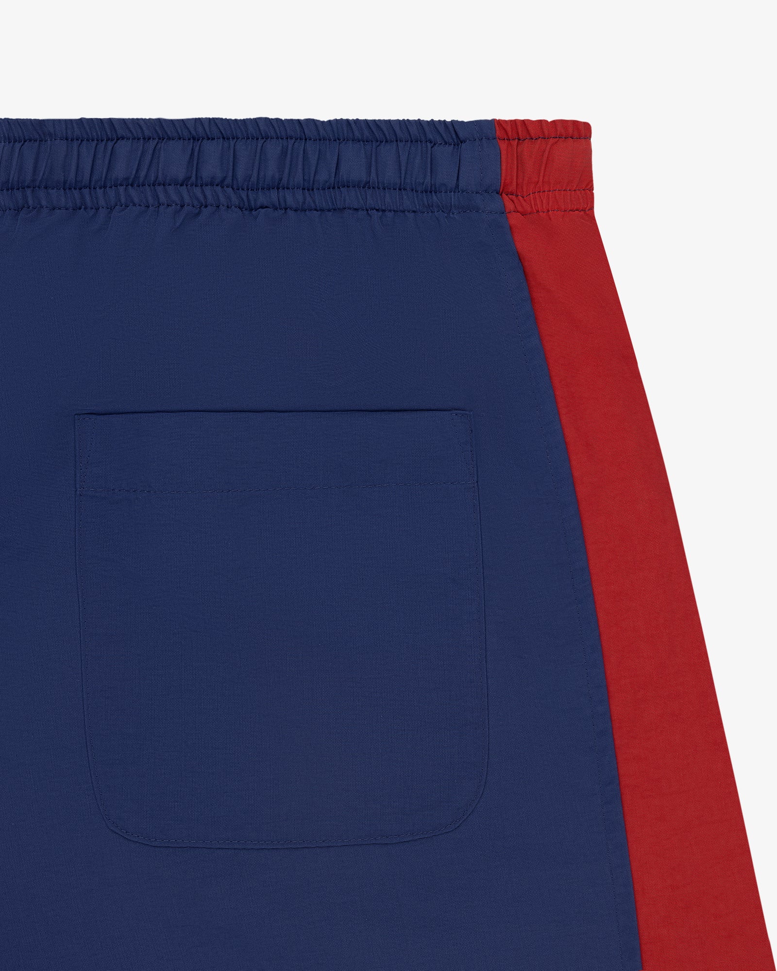 Close-up of the Colorblock Track Pant featuring a blue back pocket, red side panel, and elastic waistband detail.