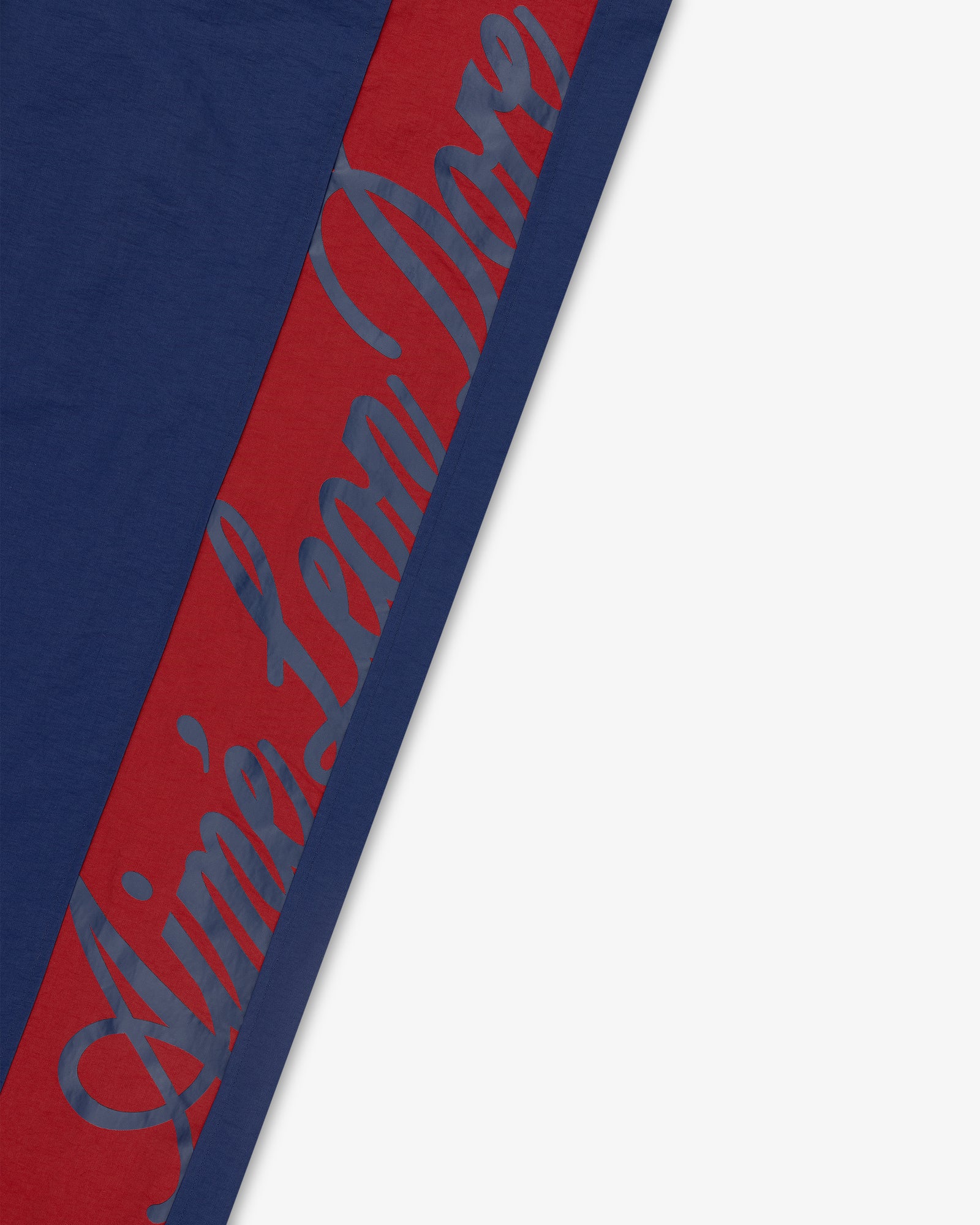 Colorblock Track Pant in navy with diagonal red stripe and subtle blue script text along the stripe.