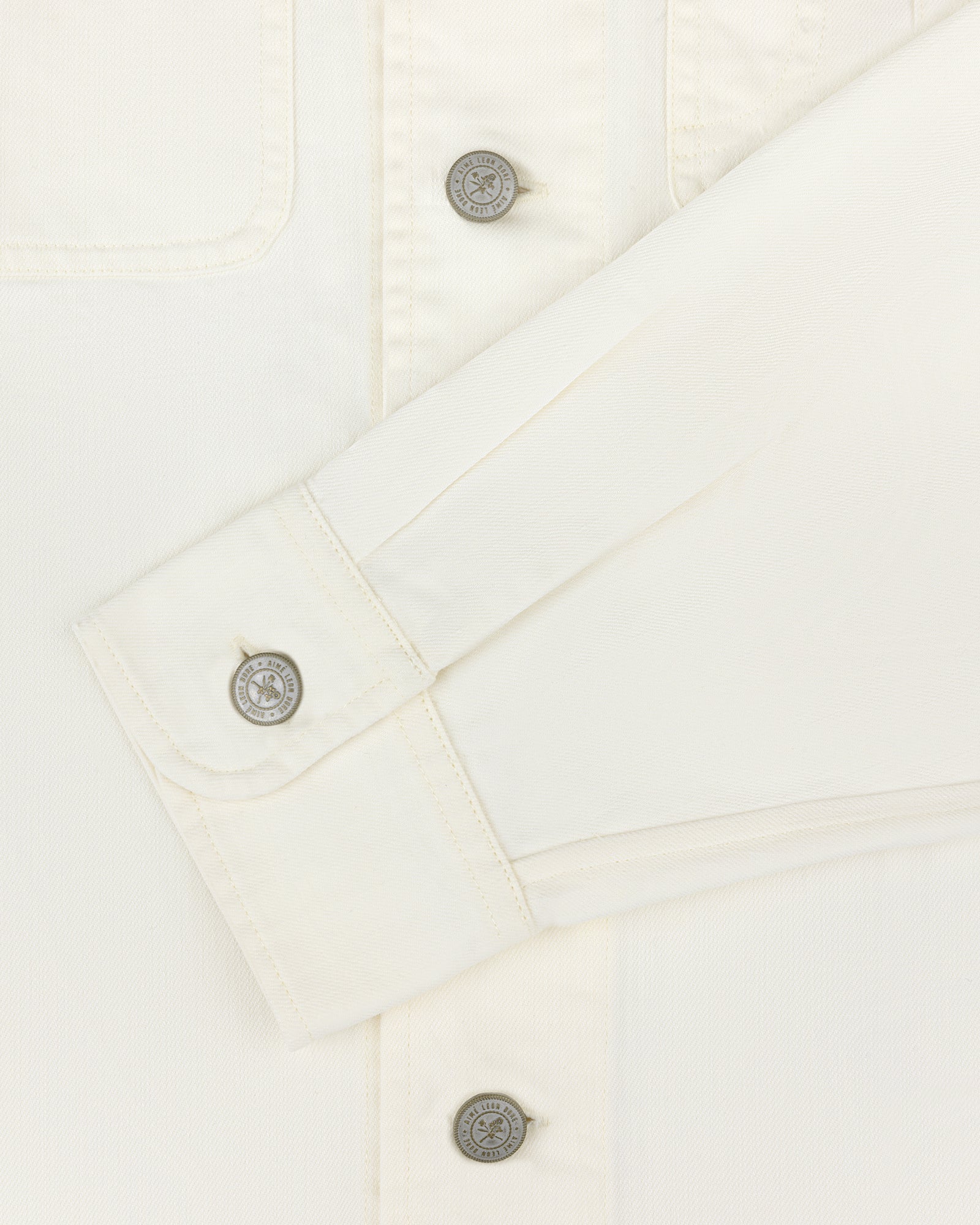 Cream Carpenter Overshirt with long sleeves and 3 buttons, including one on the cuff, neatly folded across chest.