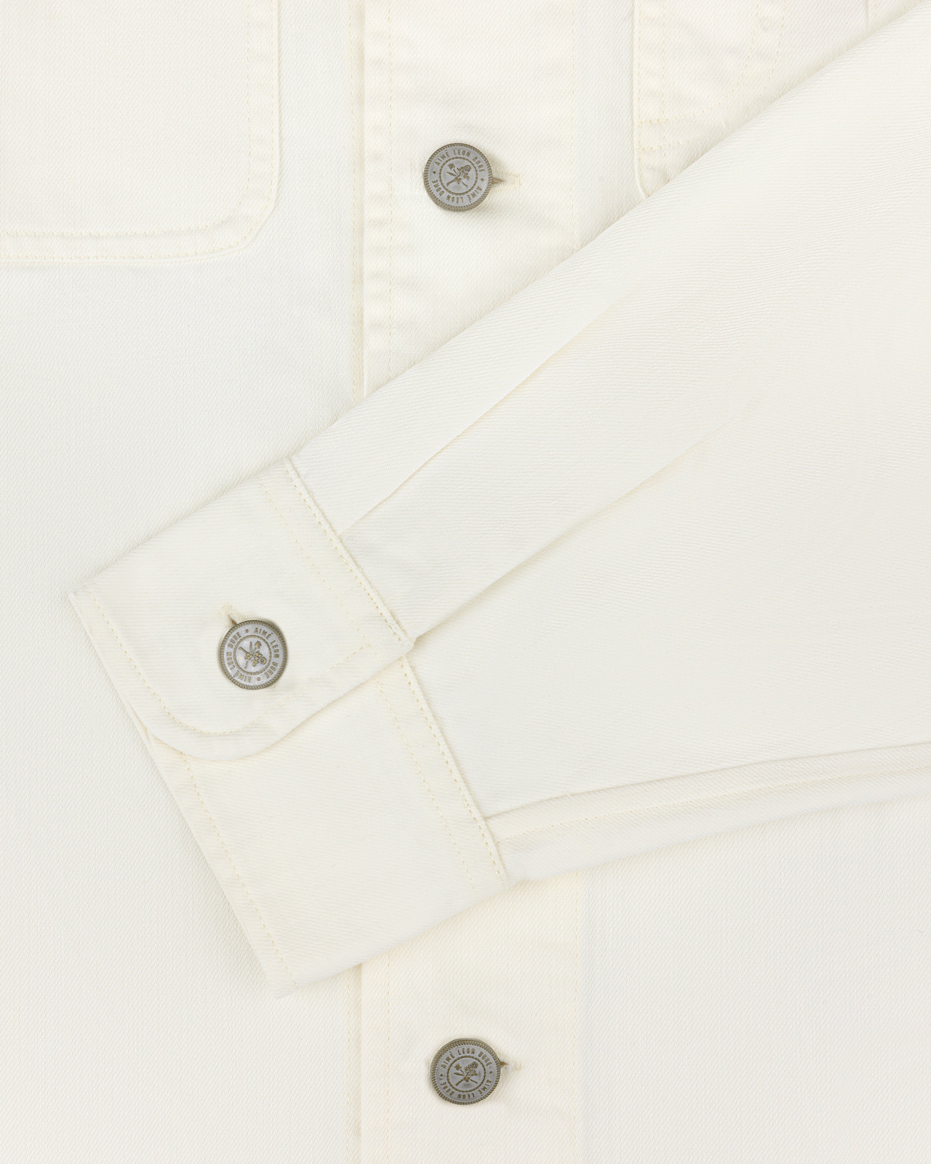 Cream Carpenter Overshirt with long sleeves and 3 buttons, including one on the cuff, neatly folded across chest.