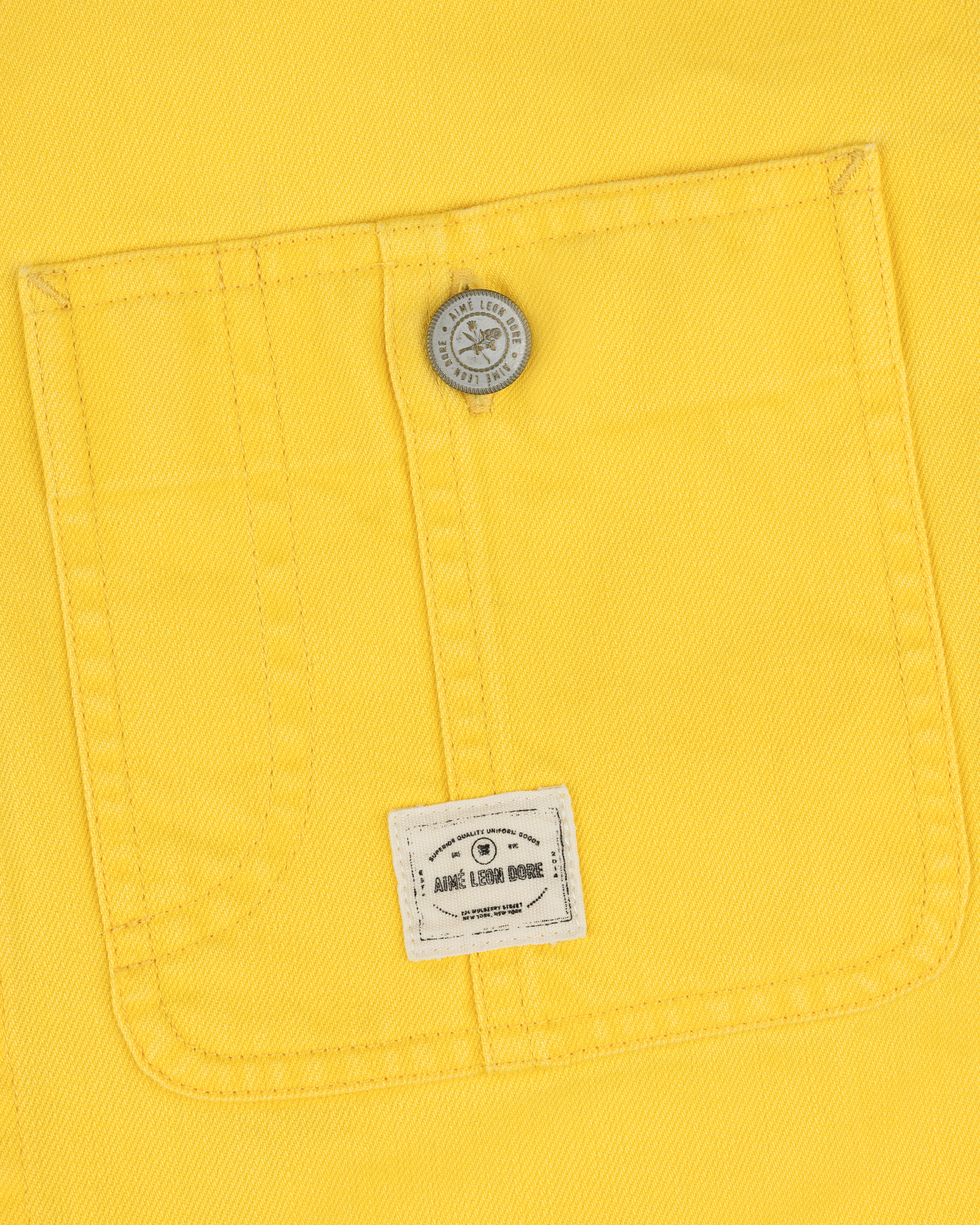 Yellow fabric pocket with a button and small white label on the Carpenter Overshirt’s lower pocket center.