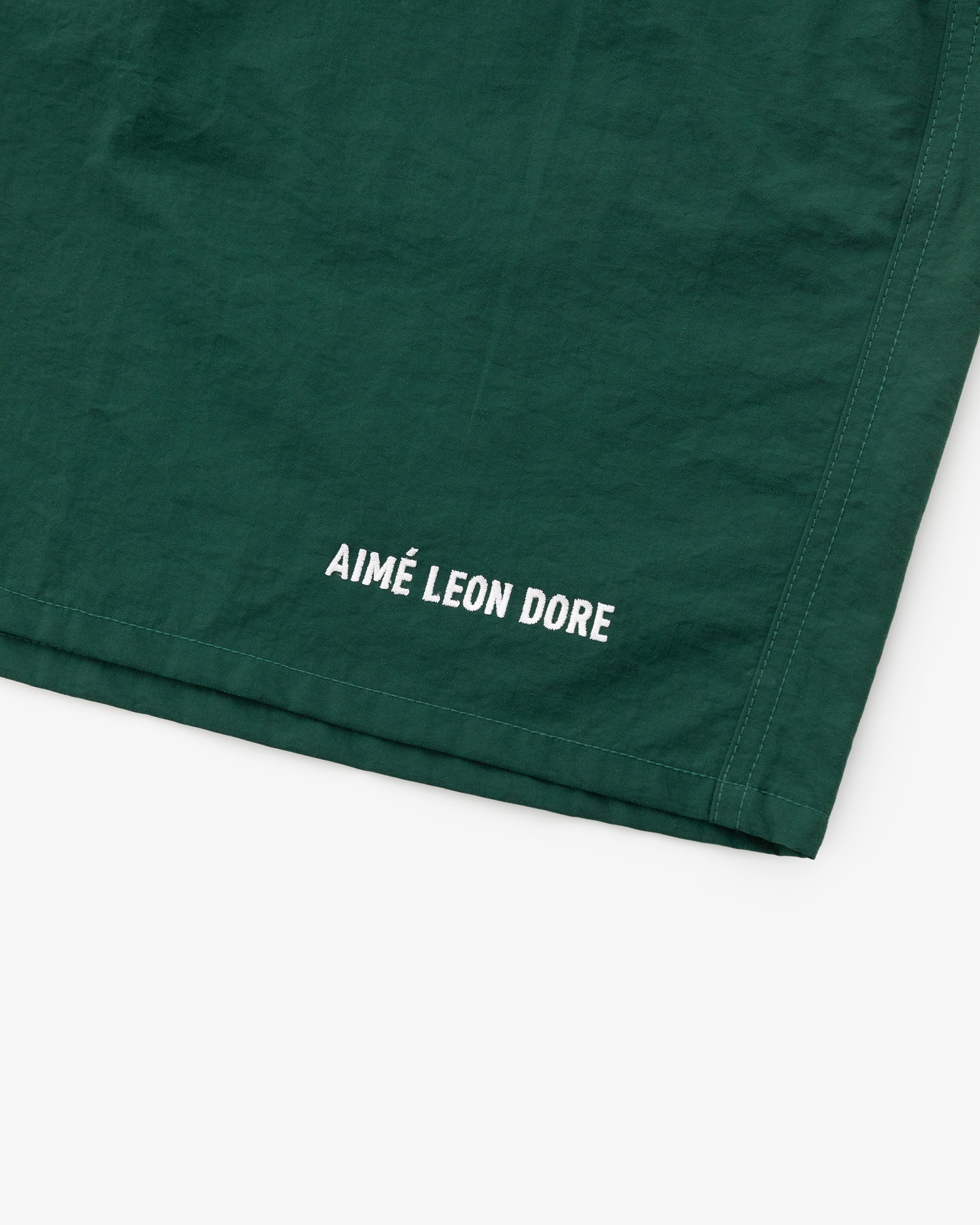 Green Logo Swim Short with white AIMÉ LEON DORE text near the hem.