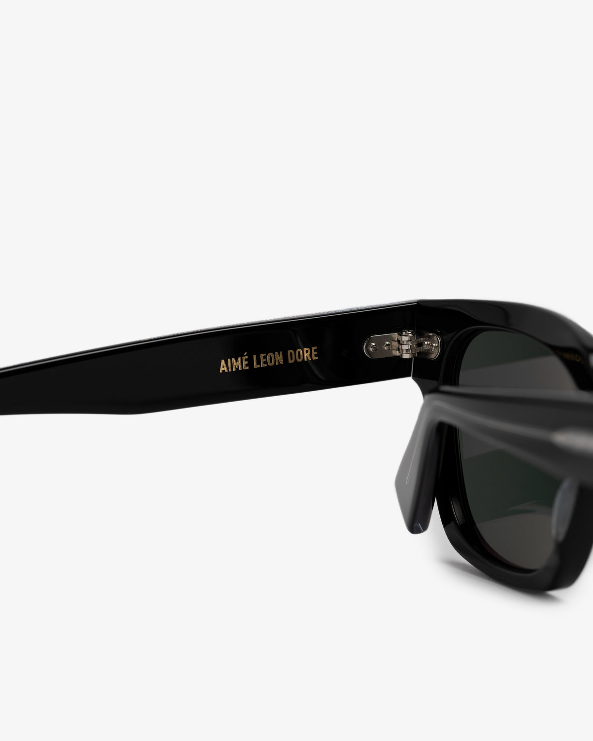 Close-up of black Gallo Sunglasses with AIMÉ LEON DORE in gold on the arm, set against a white background.