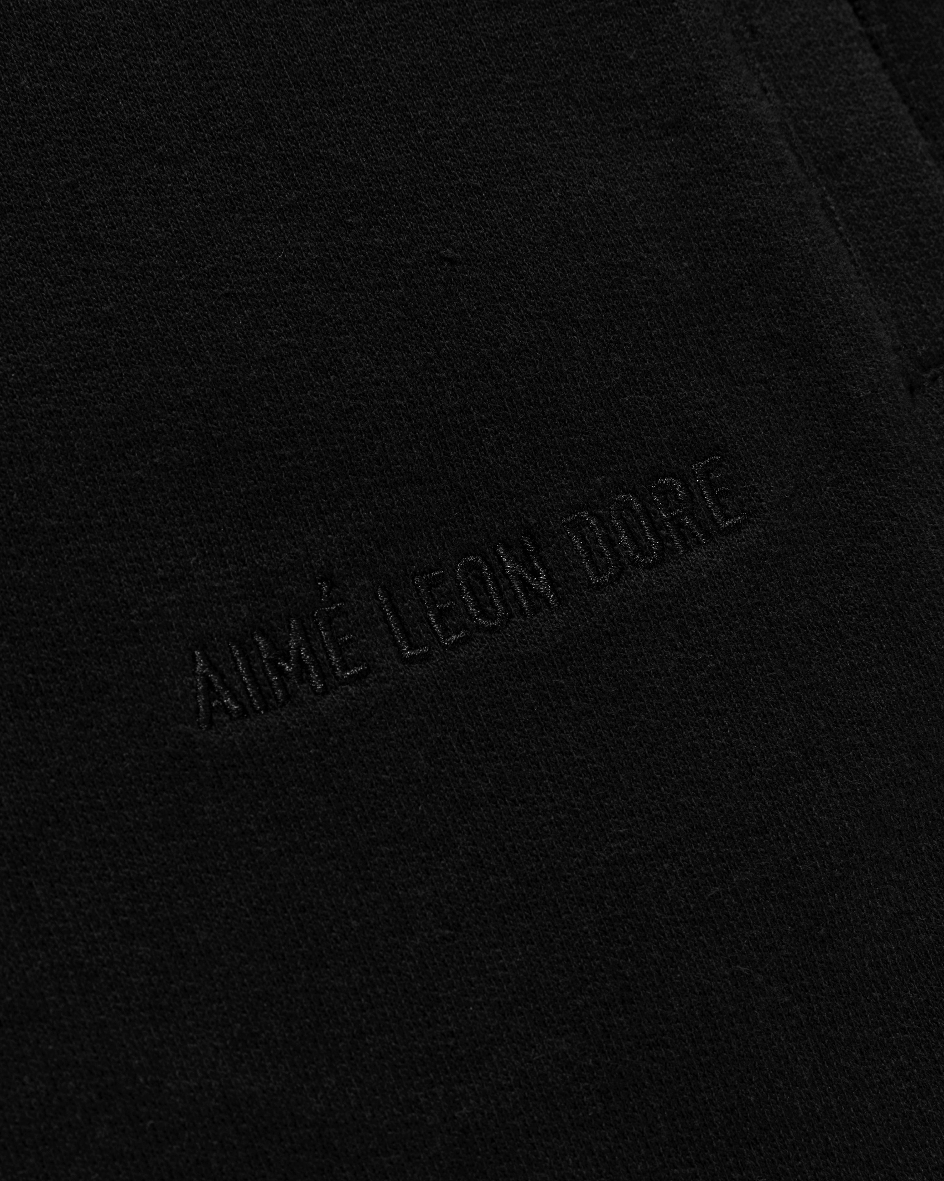 Close-up of black fabric on Tonal Logo Sweatshorts with AIMÉ LEON DORE embroidered in matching black thread.